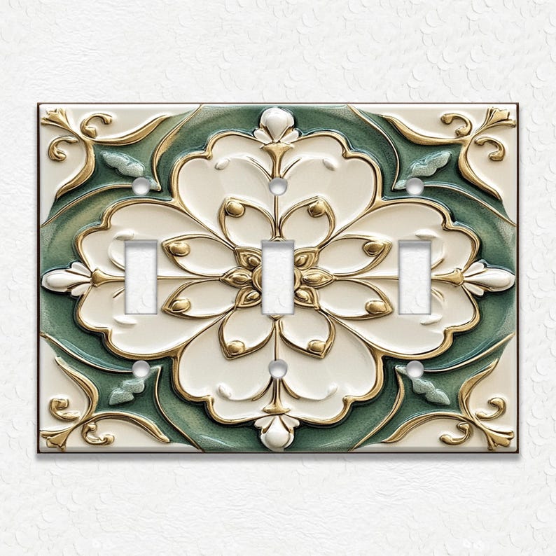 May include: A decorative triple light switch cover with a floral design. The cover features a white, green, and gold color scheme with a raised, textured pattern. The design includes a large central flower and ornate detailing.