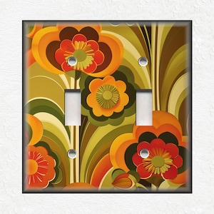 May include: A decorative double light switch cover featuring a retro floral design. The cover has a black border and a vibrant pattern of orange, red, and yellow flowers with green and brown accents. The switch openings are white.