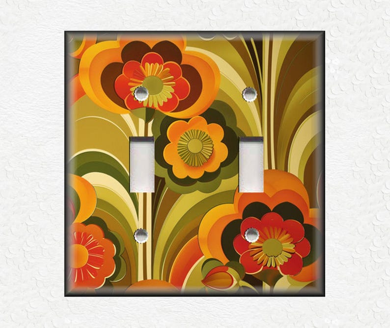 May include: A decorative double light switch cover featuring a retro floral design. The cover has a black border and a vibrant pattern of orange, red, and yellow flowers with green and brown accents. The switch openings are white.