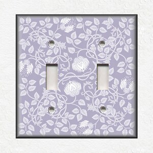 May include: A double light switch cover with a white floral pattern on a light purple background.