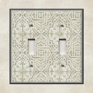 May include: A decorative double light switch cover with a patterned design in shades of blue, beige, and gray. The cover features two toggle switch openings and screw holes for mounting. The design resembles a tile pattern.
