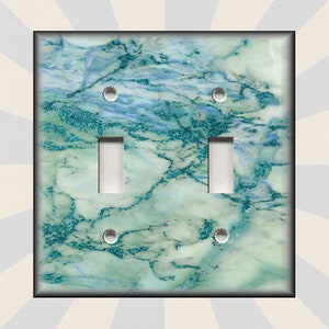 May include: A light switch cover with a teal and white marble pattern. The cover has two toggle switches and four screw holes.