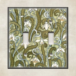 May include: A light switch cover with a floral pattern featuring white flowers and green leaves on a light green background.