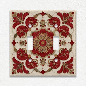 May include: A decorative light switch cover with a floral design. The cover features a cream-colored background with a repeating pattern of red and gold floral elements. The switch plate has two openings for the switches.