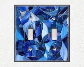Puede incluir: Una placa de interruptor de luz con un diseño de vitral con formas abstractas en tonos azules.