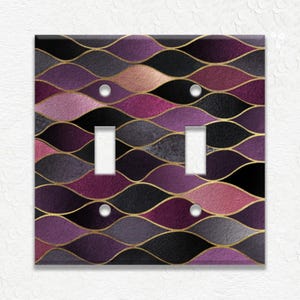 May include: A decorative double light switch cover with a wavy pattern in shades of purple, black, and rose gold, outlined with gold lines. The cover has two toggle switch openings and silver screws.