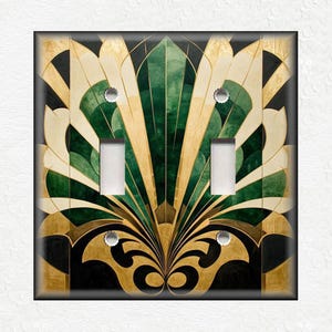 May include: A decorative light switch cover with an art deco design featuring gold, green, and black geometric shapes.