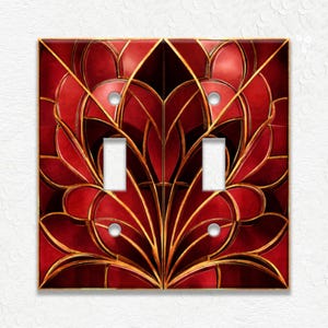 May include: A double light switch wall plate featuring a symmetrical pattern of deep red, curved petal-like shapes outlined in thin gold lines. The rectangular plate has two vertical rectangular cutouts for switches and four circular screw holes.