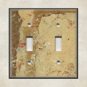 May include: A decorative double light switch cover with a vintage, textured design. The cover features a collage of torn paper in shades of beige, brown, and cream, with floral and damask patterns in red and white. The switch toggles are white.