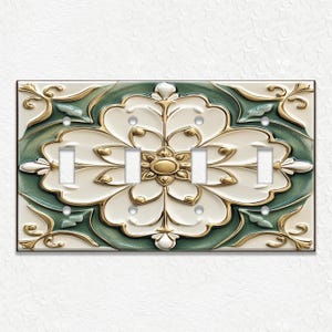 May include: A decorative light switch plate with a floral design. The plate features a large, stylized flower in white, gold, and green. The plate has four light switch openings and is mounted on a white textured wall.