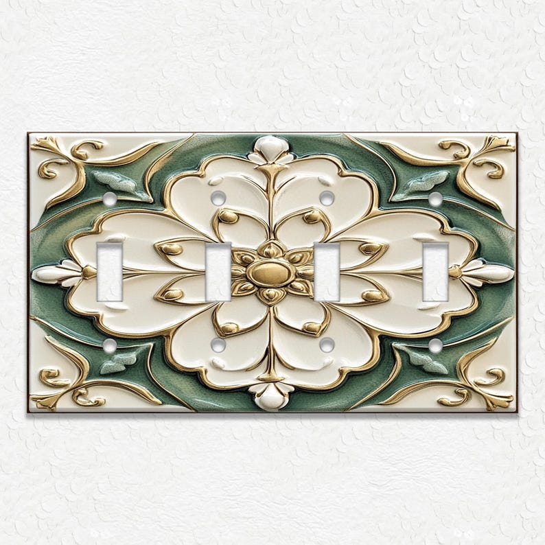 May include: A decorative light switch plate with a floral design. The plate features a large, stylized flower in white, gold, and green. The plate has four light switch openings and is mounted on a white textured wall.