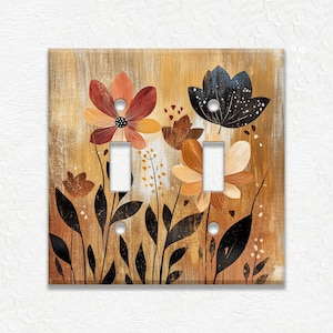May include: A light switch cover with a floral design. The background is a light brown with a wood grain texture. The flowers are in shades of orange, red, and black.
