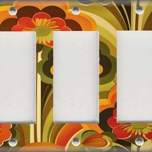 May include: A decorative triple light switch cover with a retro floral design. The cover features a vibrant pattern of orange, red, brown, and green flowers and abstract shapes. The three switch openings are white, and the screws are silver.