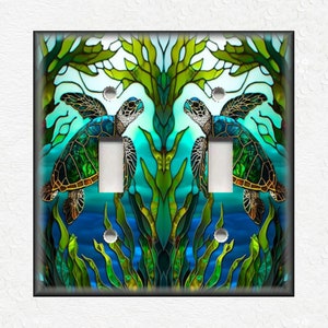 May include: A light switch cover with a stained glass design featuring two sea turtles swimming in a blue and green ocean with seaweed.