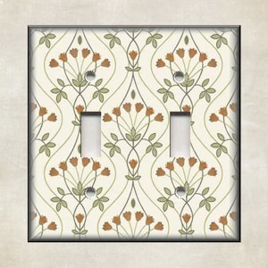 May include: A double light switch cover with a floral pattern. The pattern features brown flowers and green leaves on a white background.