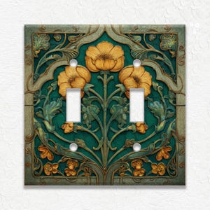 May include: A decorative double light switch cover with a floral design. The cover features a teal background with gold and green floral relief. The design includes three large flowers and smaller floral accents. The switch openings are white.