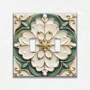 May include: A decorative double light switch cover featuring a floral design. The cover has a white, green, and gold color scheme. The floral design is centered on the cover, with two switch openings.