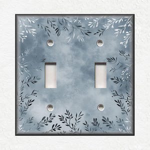 May include: A light blue light switch cover with a white and gray floral pattern.