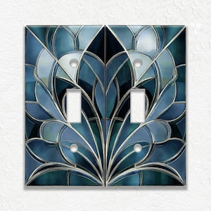 May include: A double light switch wall plate featuring a symmetrical stained glass pattern in shades of deep blue, teal, and black. The design consists of curved, petal-like shapes outlined in metallic silver lines, with two rectangular cutouts.