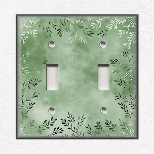 May include: A light green double light switch cover with a white and green leafy pattern.