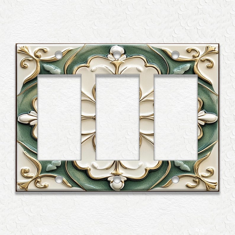 May include: Decorative triple light switch plate with a cream background and a detailed design. The plate features a green and gold floral pattern around the three switch openings. The design has a raised, textured appearance.