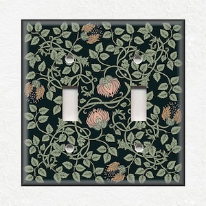 May include: A double light switch cover with a floral pattern. The pattern features green leaves, vines, and pink flowers on a dark blue background.
