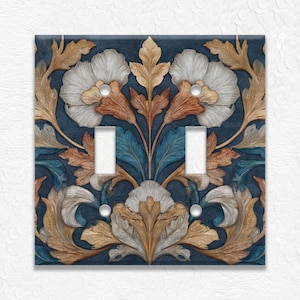 May include: A decorative double light switch cover featuring a floral design. The cover has a dark blue background with a repeating pattern of white, tan, and teal flowers and leaves. The switch openings are white.