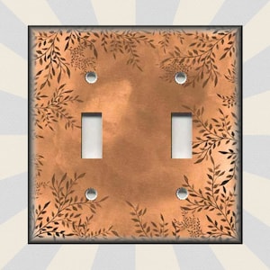 May include: A double light switch cover with a copper background and a black floral pattern.