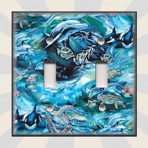 May include: A light switch plate featuring a colorful underwater scene with dolphins, sea turtles, fish, and an orca. The background is a swirling blue and green pattern.