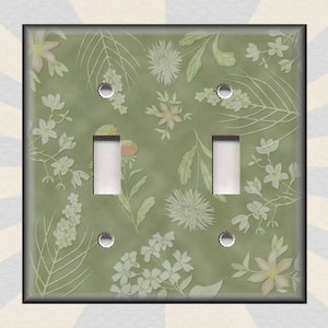 May include: A light green double light switch cover with a floral pattern. The pattern features white flowers and leaves on a light green background.