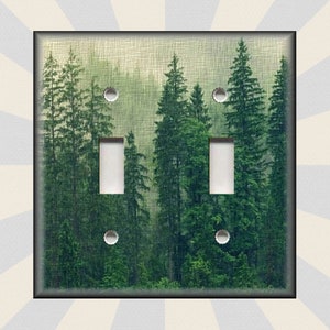May include: A light switch cover with a photograph of a misty forest with tall evergreen trees. The switch cover is white with two toggle switches.