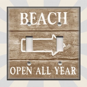 May include: A light brown wooden light switch cover with a white rope design and the text "BEACH OPEN ALL YEAR".