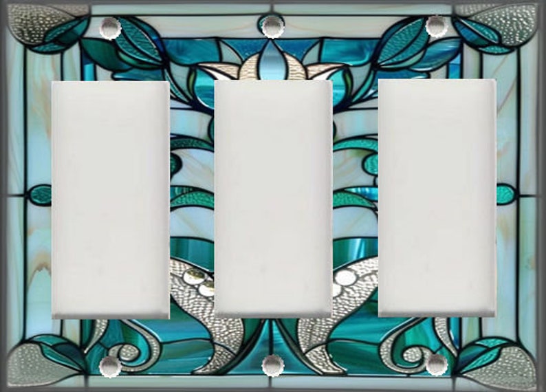 May include: A decorative triple light switch cover with a stained glass design. The design features teal, white, and silver floral and abstract patterns. The cover has three blank white switch openings and silver screw heads.