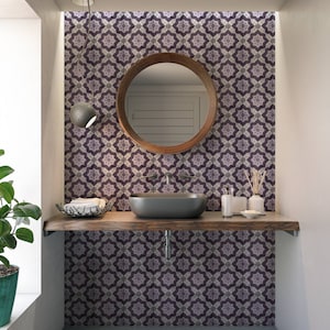 May include: A bathroom vanity with a dark wood countertop and a black sink. The backsplash is a patterned tile with purple and white geometric designs. A round mirror with a wooden frame hangs above the sink.