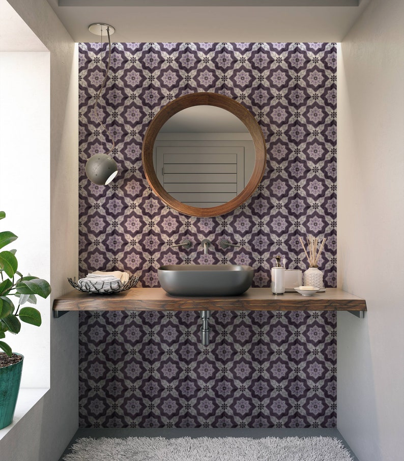 May include: A bathroom vanity with a dark wood countertop and a black sink. The backsplash is a patterned tile with purple and white geometric designs. A round mirror with a wooden frame hangs above the sink.