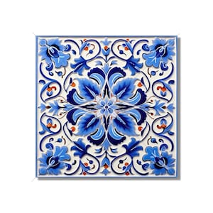 May include: A square ceramic tile with a blue and white floral pattern. The design features intricate swirls and leaves, with a central flower in shades of blue and white.