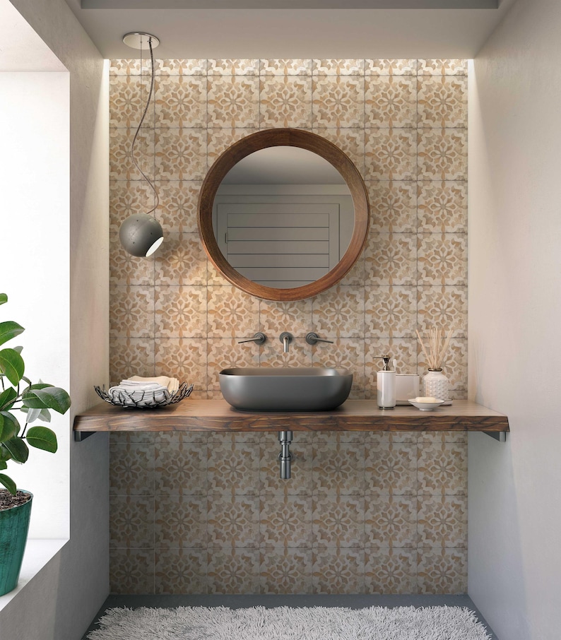 May include: A bathroom vanity with a round wooden mirror, a black sink, and a wooden countertop. The wall behind the vanity is tiled with a patterned tile in shades of beige and brown.