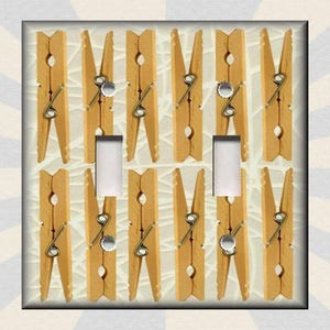 May include: A light switch cover with a design of wooden clothespins. The clothespins are arranged in a grid pattern and are all facing the same direction. The switch cover is white and has a light switch in the center.
