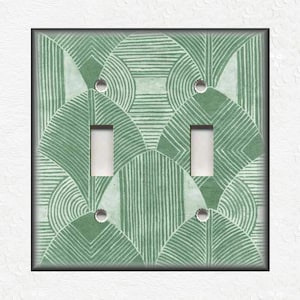 May include: A light green double light switch cover with a geometric pattern of overlapping circles and lines.