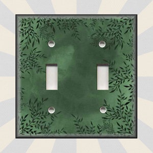 May include: A green double light switch cover with a black leafy pattern.