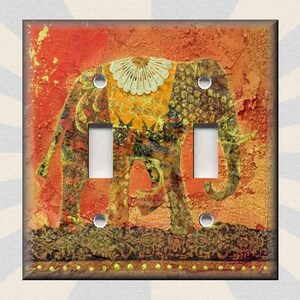 May include: A light switch cover featuring a colorful illustration of an elephant with intricate patterns and a textured background. The elephant is depicted in shades of yellow, orange, and green against a red-orange backdrop.