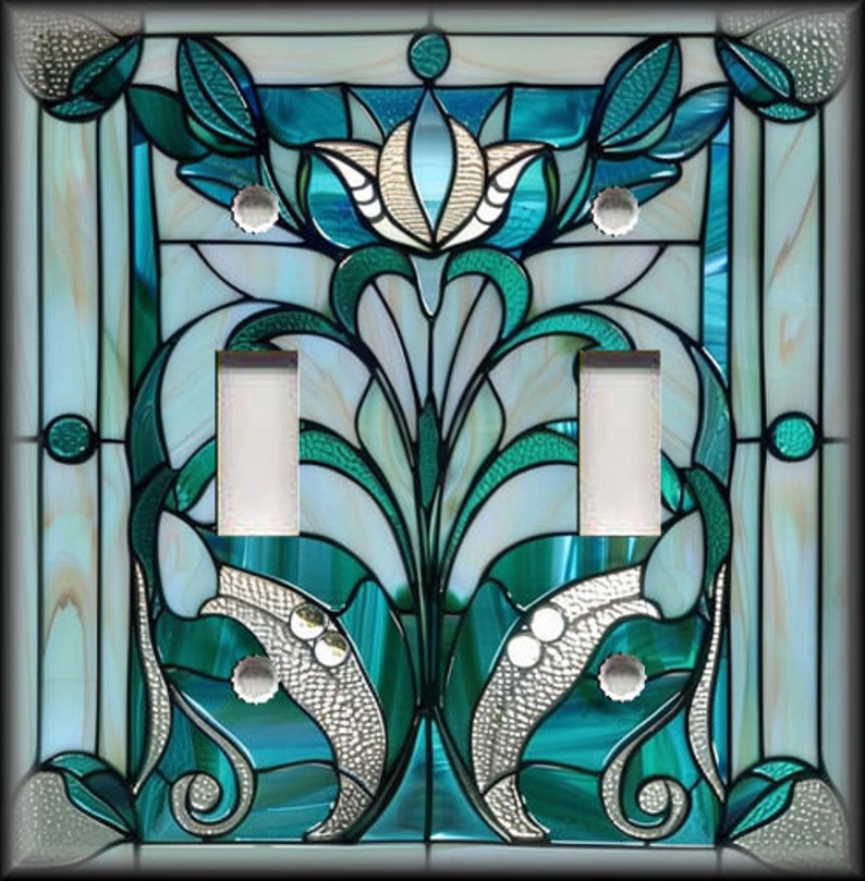 May include: A decorative light switch cover with a stained glass design. The cover features a floral pattern in shades of teal, white, and silver. The design includes two light switch openings and silver-colored screws.
