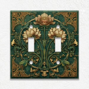 May include: A decorative double light switch cover featuring a floral design. The cover has a dark teal background with gold and tan floral accents. The design includes two light switch openings and screw holes.
