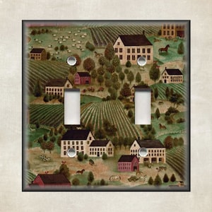 May include: A double light switch cover featuring a colorful illustration of a rural countryside scene with houses, fields, and farm animals. The scene is painted in a whimsical style with bright colors and a charming aesthetic.