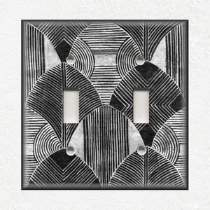 May include: Black and white geometric patterned light switch cover. The pattern features overlapping circles and lines.