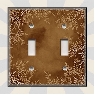 May include: A brown light switch cover with a white floral pattern. The switch cover has two toggle switches.