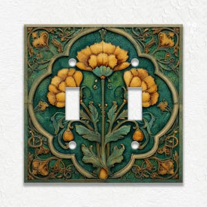 May include: A decorative double light switch cover with an Art Nouveau floral design. The cover features a teal green background with gold and yellow floral accents. The design includes two toggle switch openings and mounting screw holes.