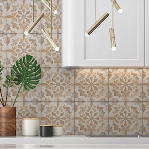 May include: A kitchen backsplash with beige and brown patterned tiles. The tiles have a floral design. There are two plants in wooden pots and three decorative containers on the counter.