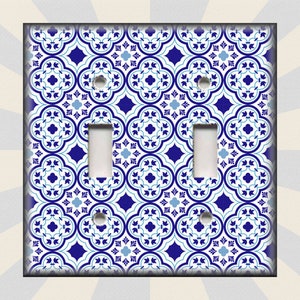 May include: A white light switch cover with a blue and white geometric pattern. The pattern features a repeating design of stylized flowers and leaves.