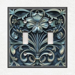 May include: A decorative light switch cover with a blue and silver floral design. The design features a large flower with intricate details and swirling vines.